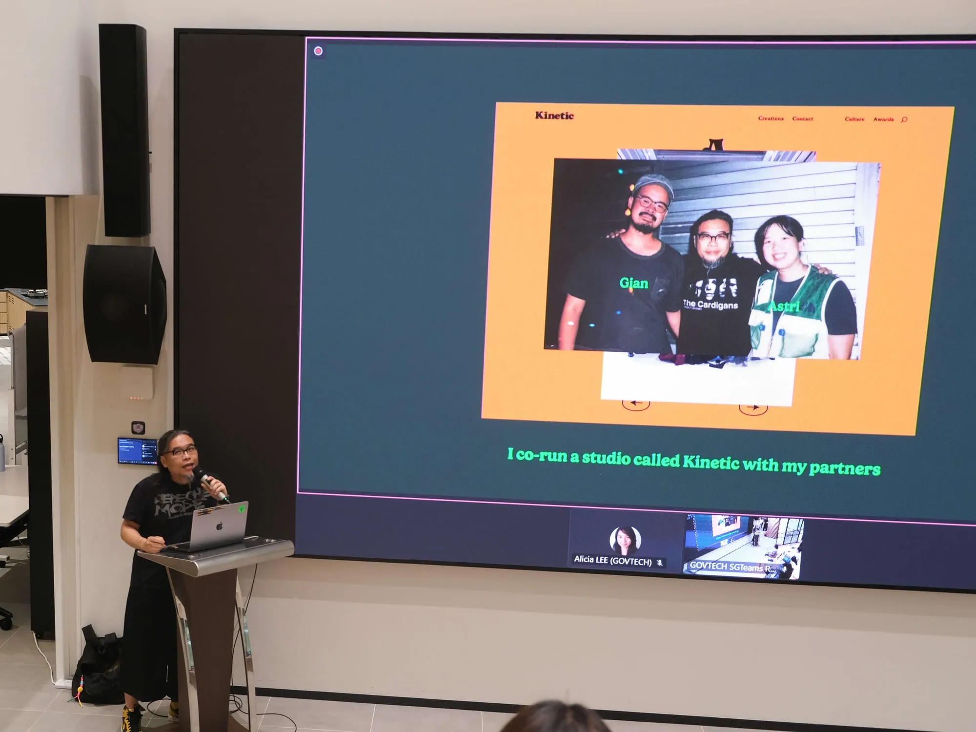 Pann at the lectern, beside a slide of him with his Kinetic partners.