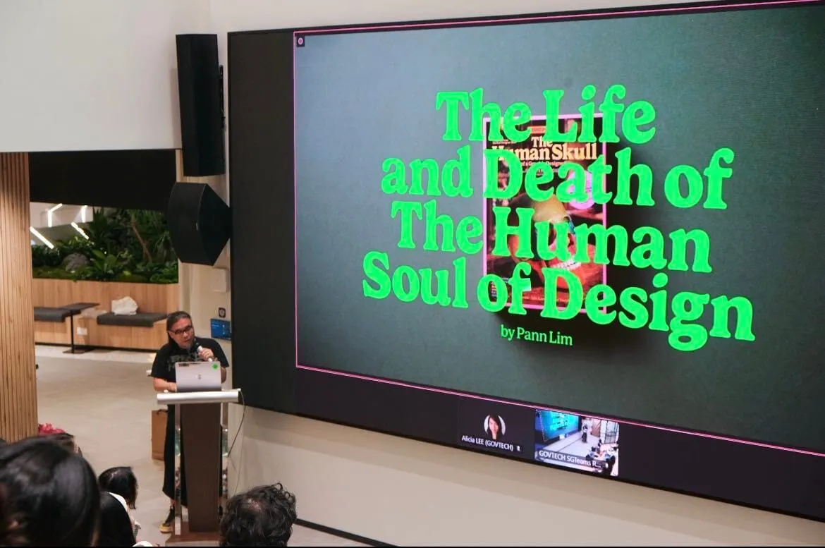 Pann Lim at the lectern, beside a screen showing the title of his talk, The Life and Death of the Human Soul of Design.